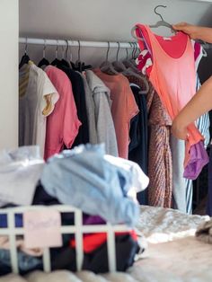 a woman standing in front of a rack with clothes on hangers and other items