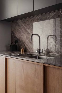 a kitchen with marble backsplash and wooden cabinetry in the corner, along with stainless steel faucets