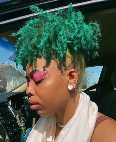 a woman with bright green hair and pink eyeliners sitting in a car looking out the window