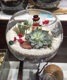 a glass bowl filled with succulents and snowmen on top of a table