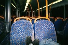 someone's feet resting on the seat of a public transit bus with blue seats