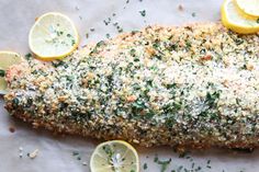 the fish is covered with parmesan and lemons on the table next to sliced lemons