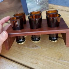 a person holding a wooden stand with four glasses on it