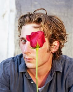 a man with long hair and a red rose in his face is looking at the camera