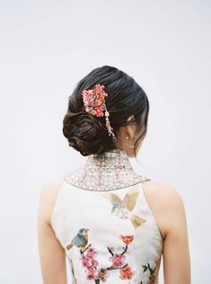 a woman in a floral dress with a bird on her head and a flowered hair clip