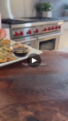 a person holding a plate with food on it in front of an oven and stove