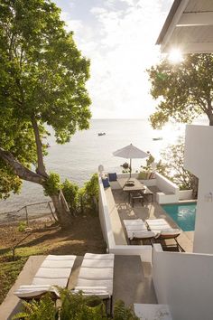 an outdoor swimming pool with lounge chairs and umbrellas next to the water's edge