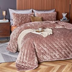 a bed covered in a pink comforter and pillows