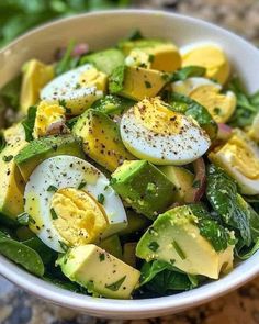 a salad with eggs and spinach in a white bowl on a marble countertop