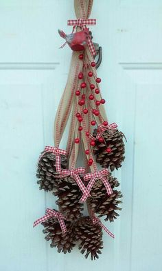 pine cones are hanging from the front door with red berries and bows on them, as if for christmas