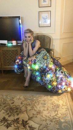 a woman sitting in a chair with a dress made out of christmas lights on it