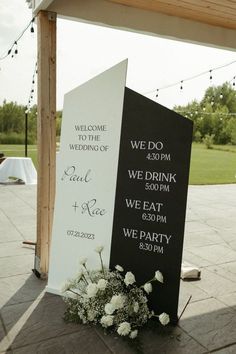 a sign that is sitting on the ground with flowers in front of it at a wedding