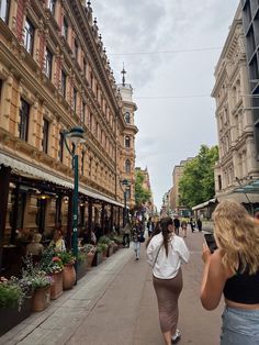 a woman walking down a street next to tall buildings