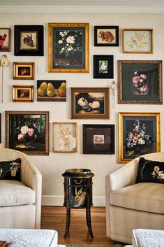 a living room filled with lots of framed pictures on the wall above two couches