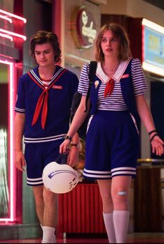 two young people in sailor uniforms are walking down the street with a white frisbee