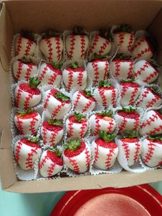 a box filled with strawberry covered donuts next to a red plate