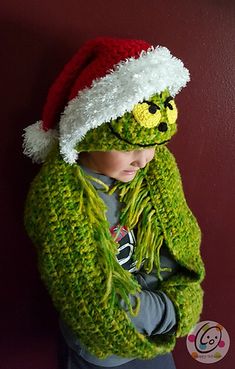 a young boy wearing a green knitted hat and scarf