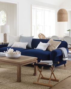 a living room with blue couches and pillows on top of the couch, coffee table