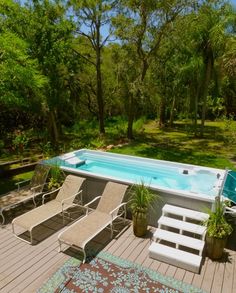 a hot tub sitting on top of a wooden deck next to a swimming pool with chaise lounges