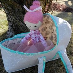 a stuffed animal in a white and blue basket on the ground next to a tree