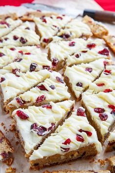 there are many pieces of cake on the table with white frosting and cranberries