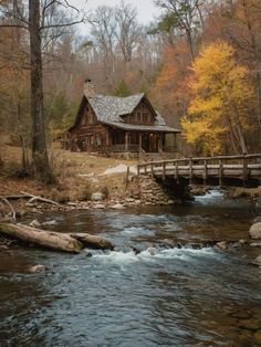 a log cabin sits on the edge of a stream in front of a wooden bridge