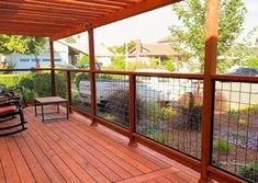 a wooden deck with two chairs and a grill on the other side that is fenced in