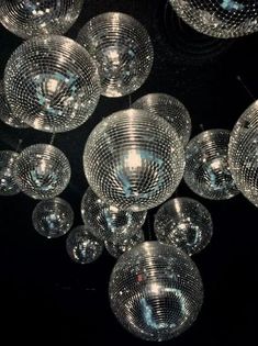 many clear glass balls hanging from the ceiling in a dark room with black walls and flooring