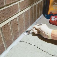 a person wearing gloves and holding a fork in front of a brick wall with adhesive tape on it