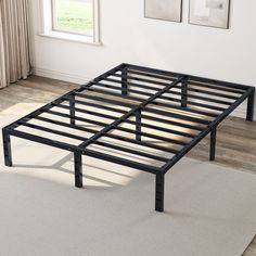 a metal bed frame sitting on top of a carpeted floor next to a window