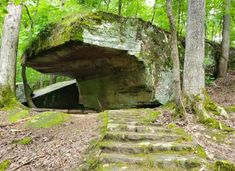 a large rock in the woods with steps leading up to it