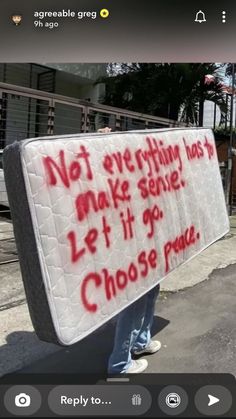 a person holding a mattress with writing on it