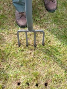 a man standing on top of a grass covered field next to a metal pole with holes in it