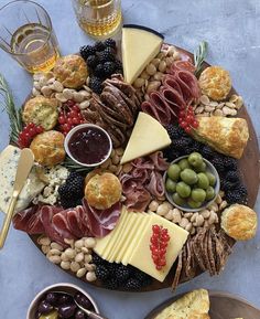 an assortment of cheeses, crackers and meats on a platter with olives