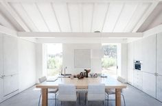 a woman standing in the middle of a kitchen with white walls and ceilinging,