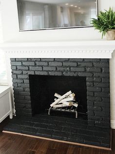 a fireplace with logs in it and a television above the fire place on the mantle