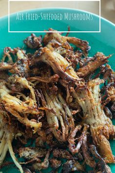 a blue plate topped with fried mushrooms on top of a wooden table and text overlay that reads air fried - shredded mushrooms