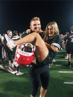 a man carrying a woman on his back at a football game with other people in the background