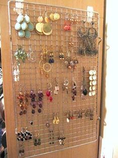 a metal rack with many pairs of earrings on it, hanging from the wall in front of a door