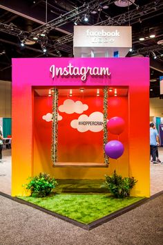 an exhibit booth with fake grass and balloons in front of the entrance to instagramm