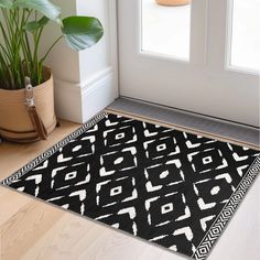 a black and white rug on the floor next to a potted plant