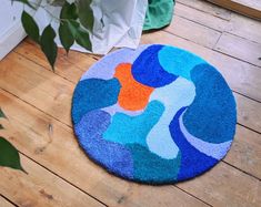 a blue and orange rug sitting on top of a wooden floor next to a potted plant