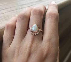 "A Genuine Natural 1 CT Opal Engagement Ring Handcrafted in your choice of Metal featuring a Pear-Shaped Cabochon Welo Opal adorned with a halo of 11 Genuine Petite White Diamond G VS 0.19ct. Wrapped in a box ready to propose to your love one. Last photo is in 18k White Gold Ring Info ----------------- Metal Options; 18k Rose Gold or White Gold or Yellow Gold Ring Shank thickness 2.3mm Model ring size 5 *Need other sizes or gemstone, convo me for pricing Halo Diamond Info ------------------ G Co Engagement Ring Teardrop, Opal Diamond Engagement Ring, Aquamarine Engagement Ring Vintage, Opal Engagement Ring Rose Gold, Pear Engagement Ring Halo, Cultural Wedding, Ring Teardrop, October Birthstone Ring, Rose Gold Opal Ring