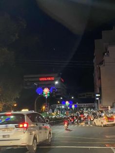 a busy city street at night with cars and motorcycles driving down the middle of it