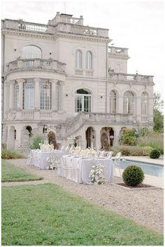 an elegant wedding set up in front of a large house with white linens and flowers