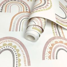 a wallpaper with rainbows and circles on white paper, next to a roll of tape