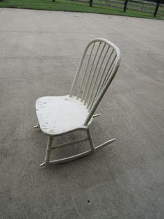 a white rocking chair sitting on top of a cement ground