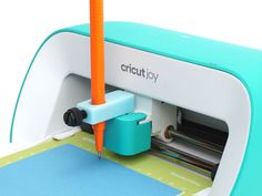 a blue and white cricutjoy machine sitting on top of a green table