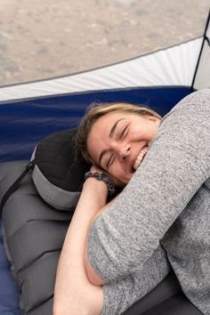 a woman laying on top of an inflatable mattress next to a blue car