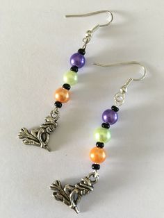 a pair of earrings with colorful beads and charms on the earwires are hanging from silver hooks